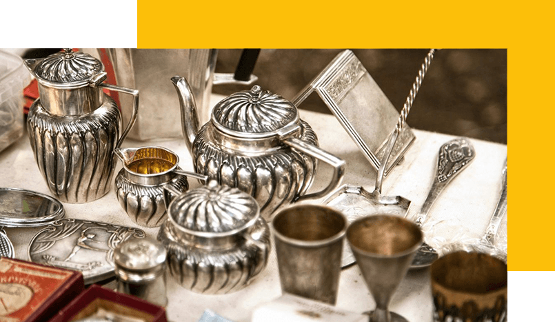 A table with silver tea pots and cups on it.