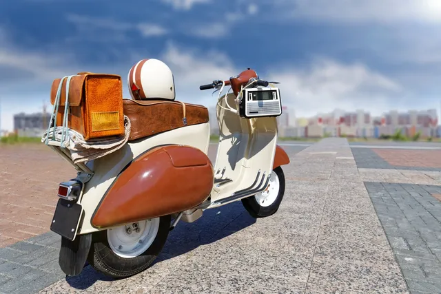A brown and white scooter parked on the side of a road.