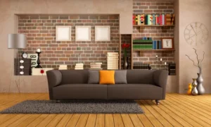A couch in front of a brick wall with books on the shelves.